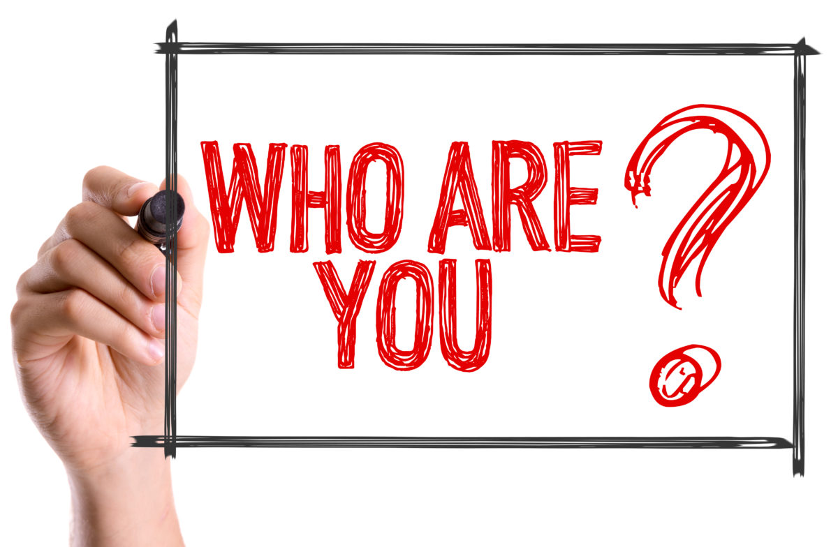 A hand writing on a whiteboard that reads, "Who Are You?"