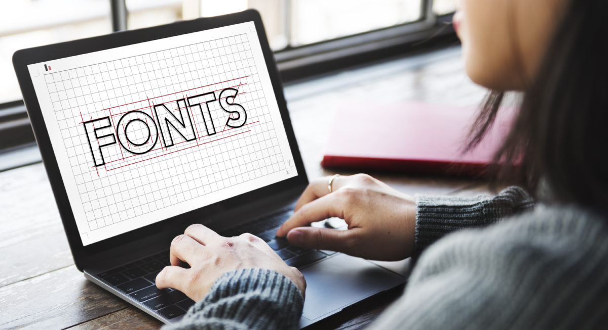 A woman on her laptop with the word "FONTS" on the screen in all caps