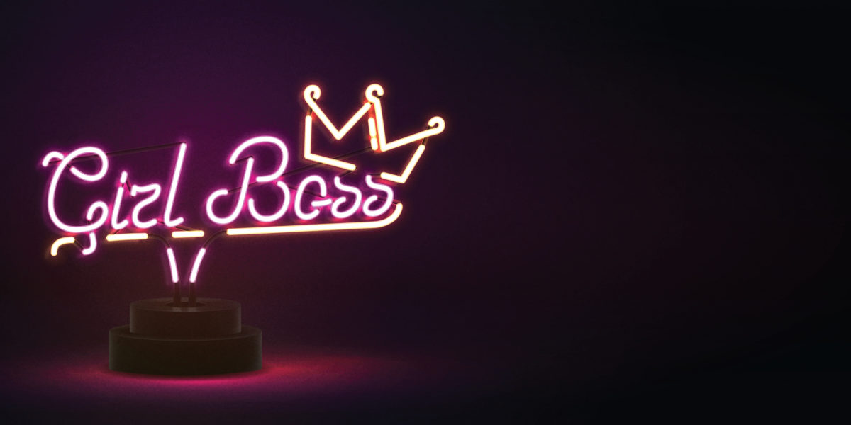 A neon light that says "Girl Boss" in pink with a top crown