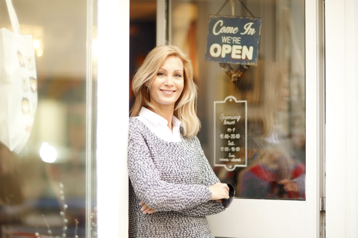 A woman stands outside of the small business she owns