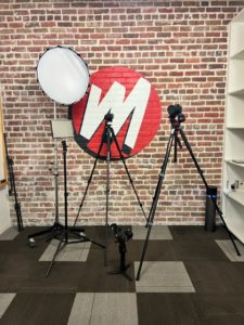 Several pieces of production equipment stand in front of a wall bearing the Mad Men Marketing logo