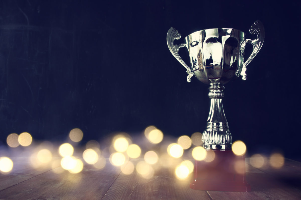 A trophy stands on a wooden floor with many sparkles in the forefront